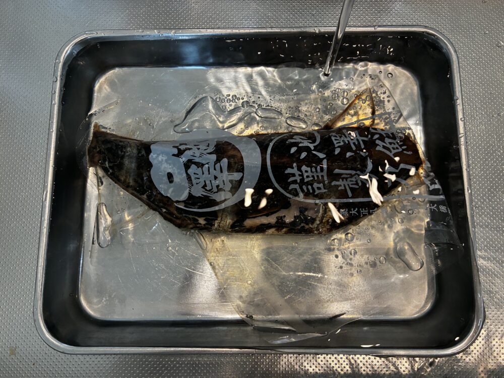 バットに溜めた流水で池澤鮮魚の冷凍カツオを解凍する様子