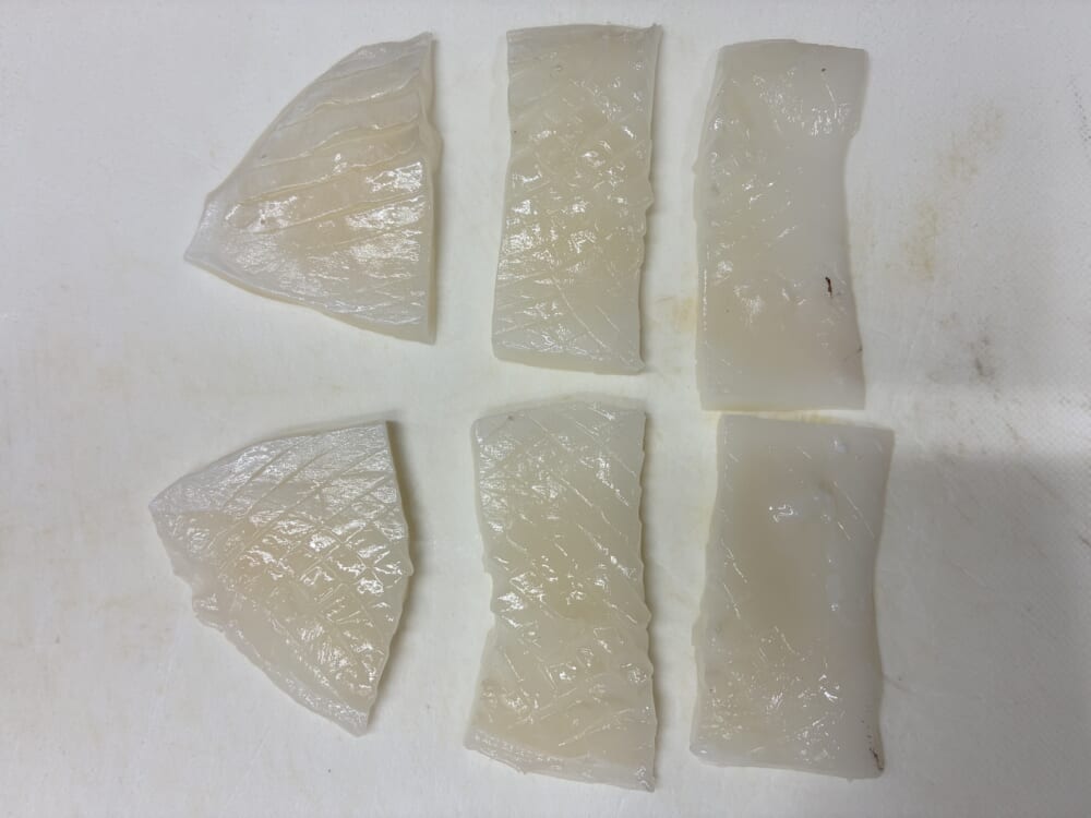 格子状の隠し包丁を入れたイカの身を一口大の長方形に切り揃えた様子