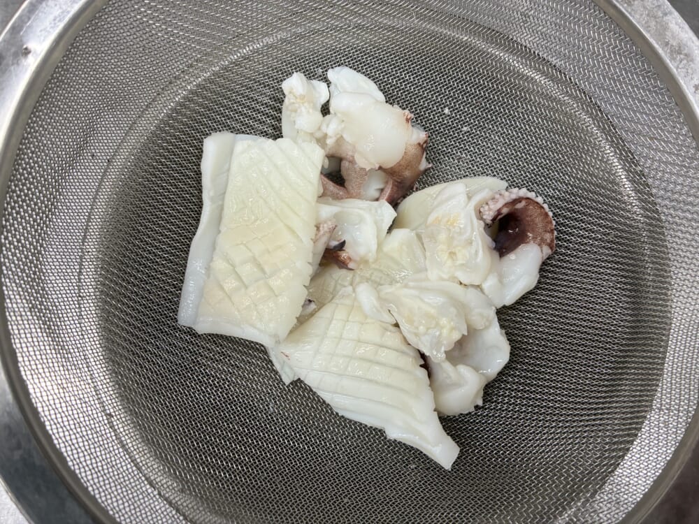 お湯から引き揚げ、しっかり水分を切るためにボウルとザルにあげたイカ