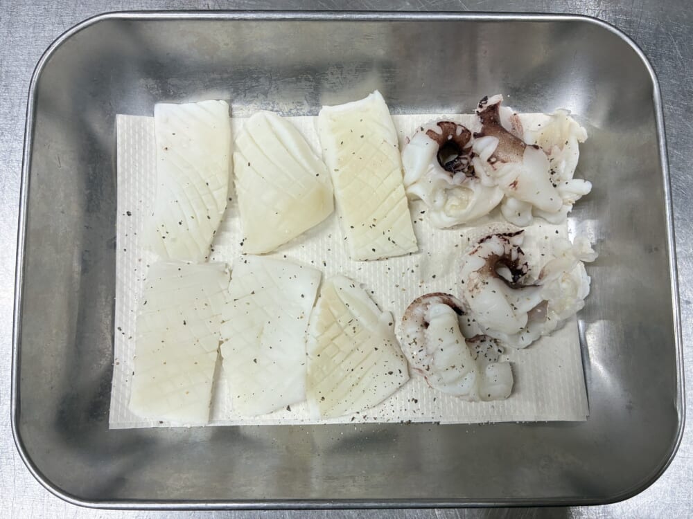 水分を完璧に拭き取ったイカの身とゲソに塩コショウで下味をつけてバットに並べた様子