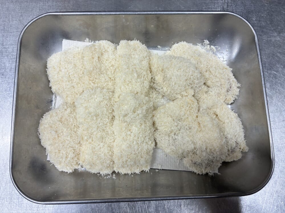 バッター液と生パン粉をつけ、揚げる際に衣が剥がれたり油が跳ねたりしないようバットで5分ほど馴染ませているイカフライ