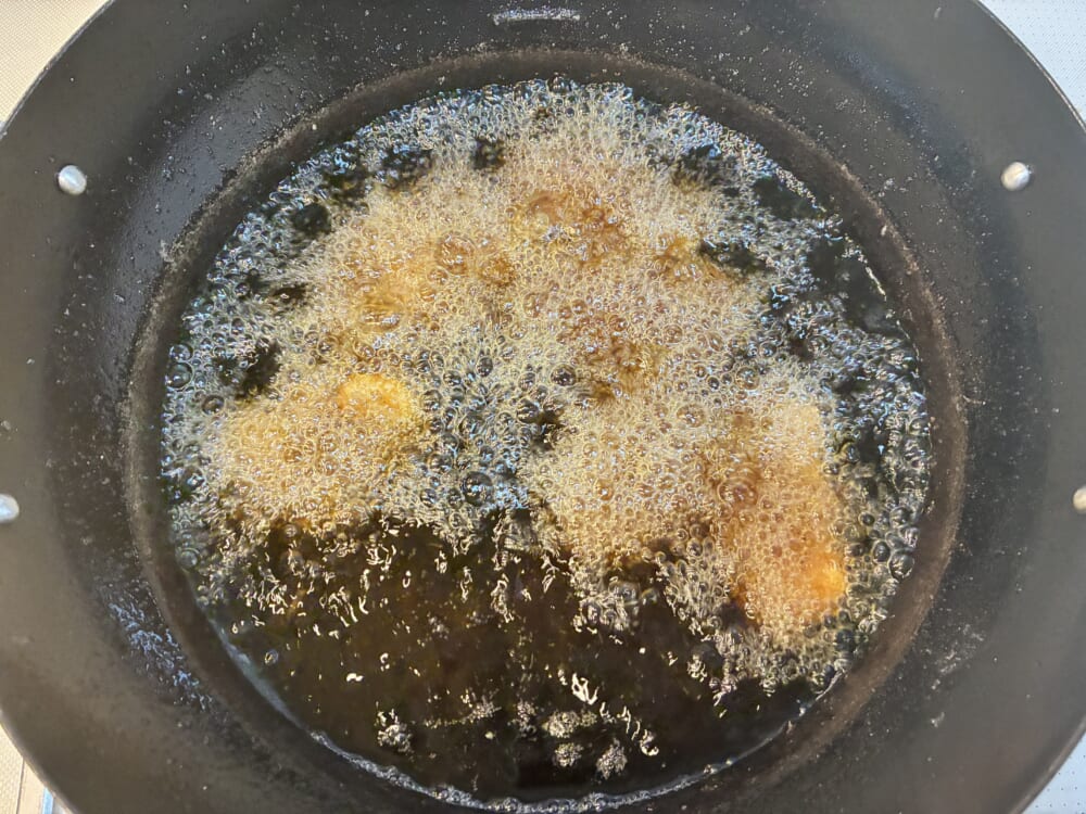 170〜180℃の中温の油でイカフライをきつね色に揚げている様子